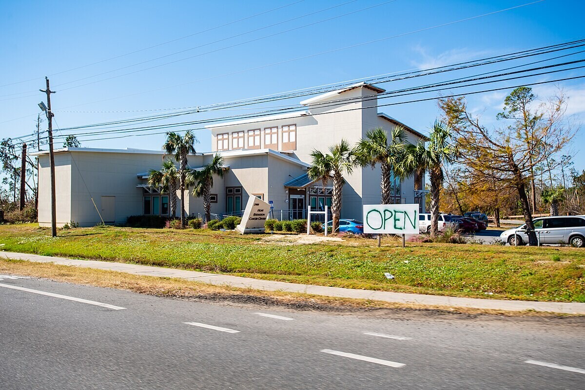 A hurricane-damaged building with an "open" sign out front