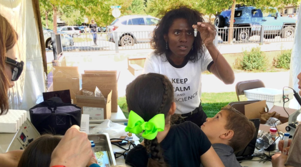 A woman performs a science experiment while children watch